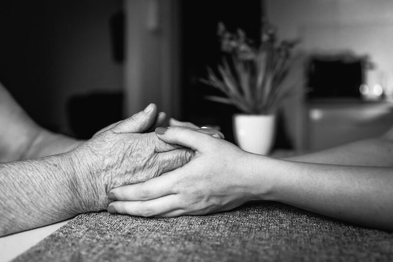 Old and young female hands are holding, elderly care and respect, close-up.